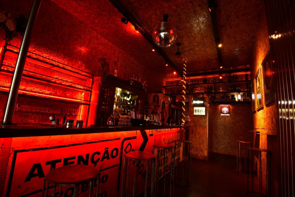 Balcão de bar revestido com placas de sinalização de trânsito, luz vermelha, prateleiras de copos e globo espelhado